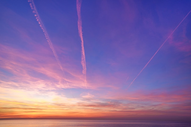 Incantando il gradiente magico del cielo con le tracce dell'aereo dopo il tramonto