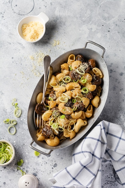 Incolla Pipa Rigate e Funghi champignon fritti in salsa di soia, con pepe, parmigiano e cipolle al vapore in una vecchia ciotola di metallo su un vecchio tavolo vintage