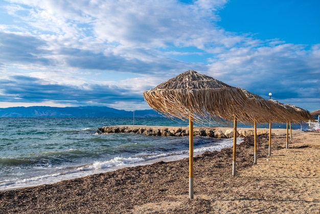 Incredibile baia con acqua cristallina sull'isola di Corfù, in Grecia. Bellissimo paesaggio della spiaggia del Mar Ionio con ombrelloni di paglia, giornata di sole.