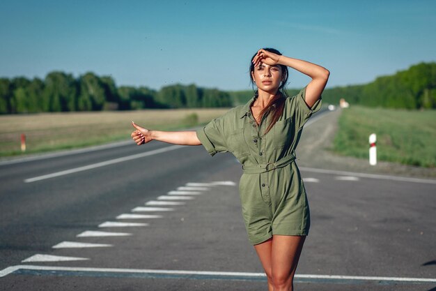 Incredibile bella signora con le gambe snelle sta facendo l'autostop in mezzo alla strada