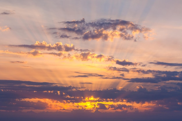 Incredibile cielo al tramonto con uno sfondo naturale di raggi di sole dorati reali