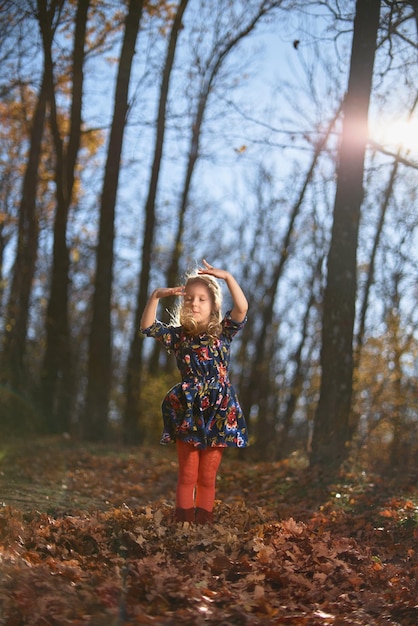 Incredibile foglia Ragazza carina in un grande mucchio di fogliame Bambina bambina piace giocare all'aria aperta