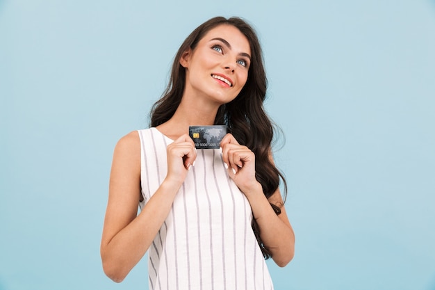 Incredibile giovane donna in posa muro isolato tenendo la carta di credito.