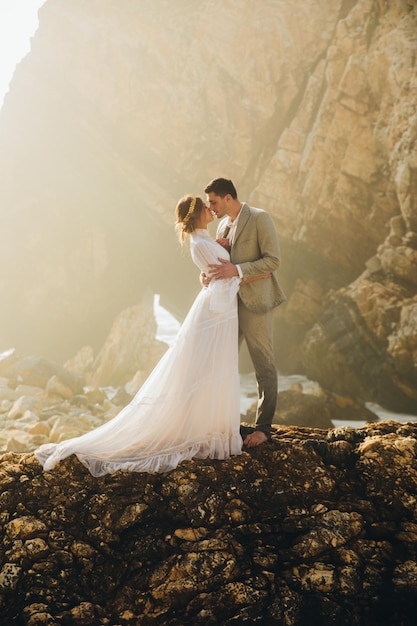 Incredibile immagine della giovane sposa delle coppie in abito lungo con il suo sposo nell'oceano