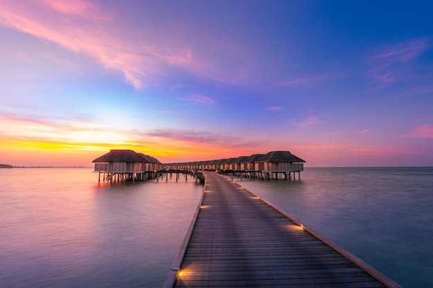 Incredibile panorama al tramonto alle Maldive Ville di resort di lusso con vista sul mare con luci a led soffuse e cielo colorato