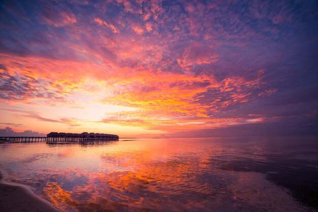 Incredibile panorama al tramonto alle Maldive. Ville resort di lusso vista sul mare baia bellezza riflesso della superficie del mare
