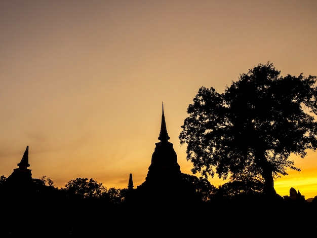 Incredibile scenografia di silhouette di pagoda, tempio e cielo al tramonto d'oro nel parco storico di Sukhothai, patrimonio mondiale dell'UNESCO in Thailandia.