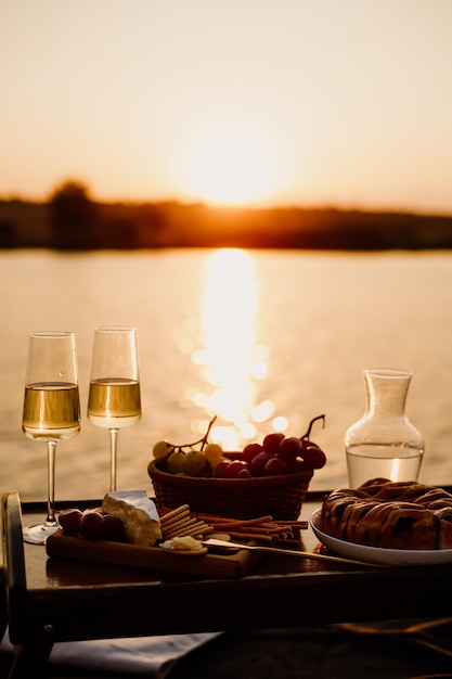 Incredibile tramonto sul lago, vino bianco, torta di frutta, mele, uva, brie, biscotti. Autunno.