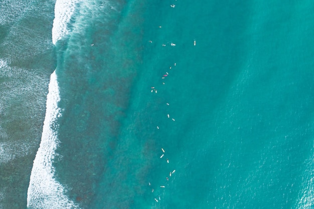 Incredibile vista aerea Dall'alto verso il basso delle onde si infrangono sul mare tropicale Surfisti con tavole da surf Vista aerea dei droni delle onde del mare sull'oceano di superficie del mare bellissimo a Phuket Thailandia.