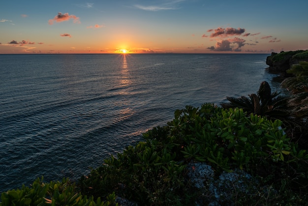 Incredibile vista dall'alto del tramonto della costa all'orizzonte. Mare di superficie ondulato a causa del vento costiero, vegetazione sulla scogliera.