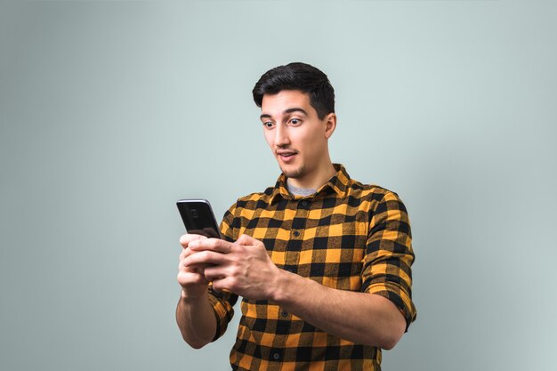 Incredibili buone notizie. uomo sorpreso in camicia gialla in possesso di un telefono