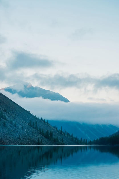 Incredibili sagome di montagne e nuvole basse riflesse sul lago di montagna