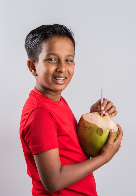 India ed estate - Carino piccolo ragazzo indiano che beve acqua di cocco per tenerlo disidratato, isolato su sfondo bianco