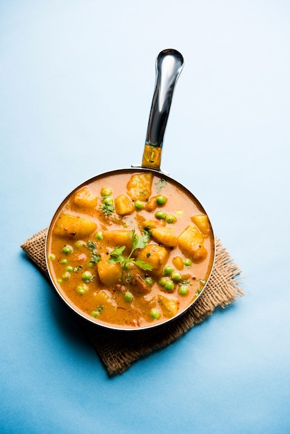 Indian Aloo Mutter curry - Patate e piselli immersi in un sugo di cipolla e pomodoro e guarniti con foglie di coriandolo. Servito in un Karahi o un kadhai o una padella o una ciotola