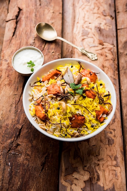 Indian Chicken Tikka Biriyani servito in una ciotola con yogurt. messa a fuoco selettiva