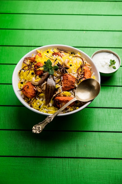 Indian Chicken Tikka Biriyani servito in una ciotola con yogurt. messa a fuoco selettiva