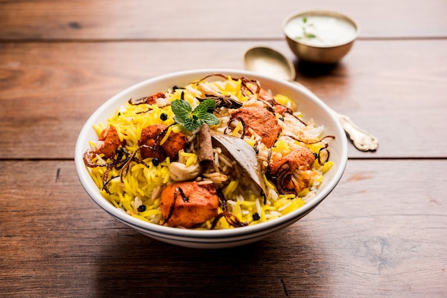 Indian Chicken Tikka Biriyani servito in una ciotola con yogurt