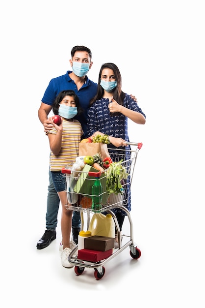 Indian Family Shopping con i bambini durante l'epidemia di virus. Madre, padre e figlia che indossano una maschera chirurgica per l'acquisto di generi alimentari al supermercato. Famiglia in negozio.