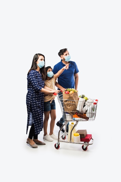 Indian Family Shopping con i bambini durante l'epidemia di virus. Madre, padre e figlia che indossano una maschera chirurgica per l'acquisto di generi alimentari al supermercato. Famiglia in negozio.