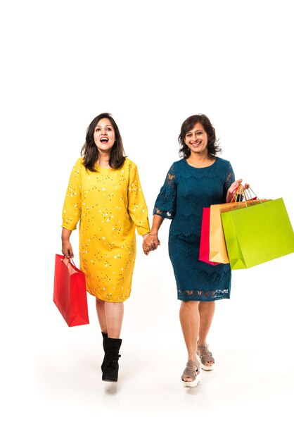 Indian madre figlia sorelle shopping con borse colorate, in piedi isolato su sfondo bianco