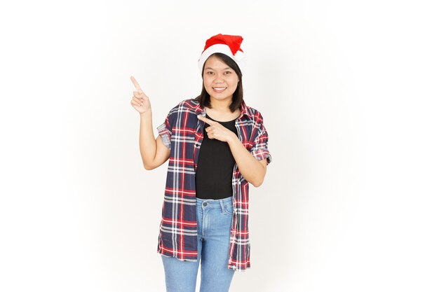Indicare e presentare da parte una bella donna asiatica che indossa una camicia scozzese rossa e un cappello da Babbo Natale