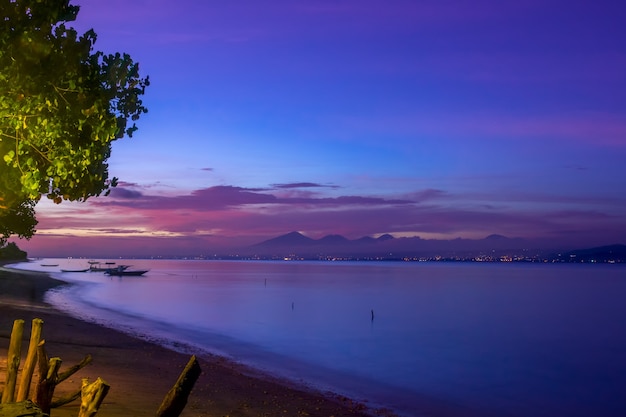 Indonesia. Costa della baia tra le isole dopo il tramonto. Barche e luci dell'altra sponda