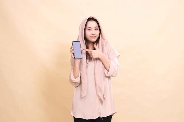 indonesia donna sorride alla telecamera tenendo la mano e indicando lo schermo del cellulare gadget giovane beautif