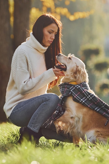 Indossare la sciarpa Giovane donna fare una passeggiata con Golden Retriever nel parco