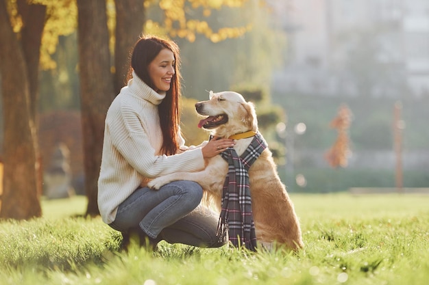 Indossare la sciarpa Giovane donna fare una passeggiata con Golden Retriever nel parco