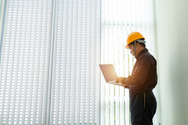 Industrial Engineer in Hard Hat Wearing Safety Jacket utilizza laptop touchscreen.