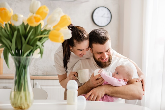 Infante d'alimentazione della giovane famiglia felice nella cucina