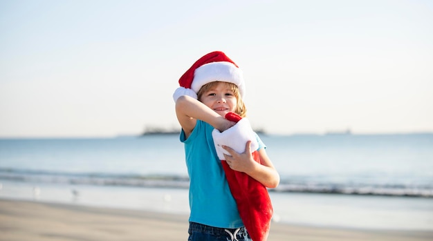 Infanzia e capodanno carino bambino in cappello rosso santa con calza di natale nella soleggiata giornata invernale