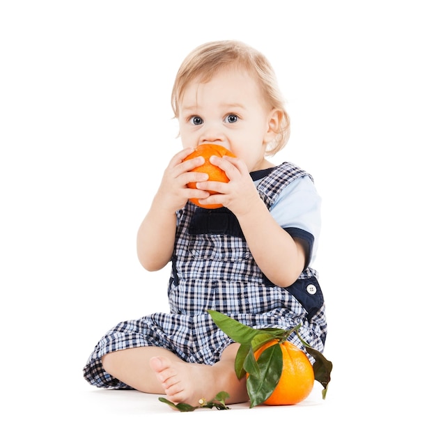 infanzia e concetto di cibo sano - bambino carino che mangia arancia