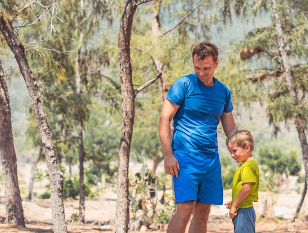 Infanzia felice Tempo di paternità foto Papà figlio sorriso ridere stare in estate giorno foresta guardare in basso esplorare qualcosa casa educazione naturale festa del papà bambino visione del mondo formazione papà amore sentimenti