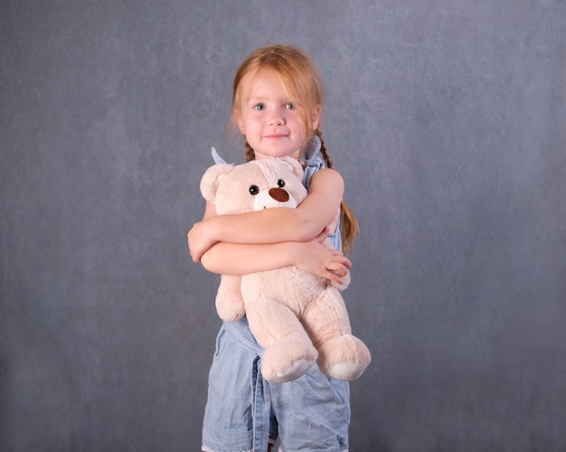 Infanzia, giocattoli e concetto di shopping. bambina carina che abbraccia l'orsacchiotto.