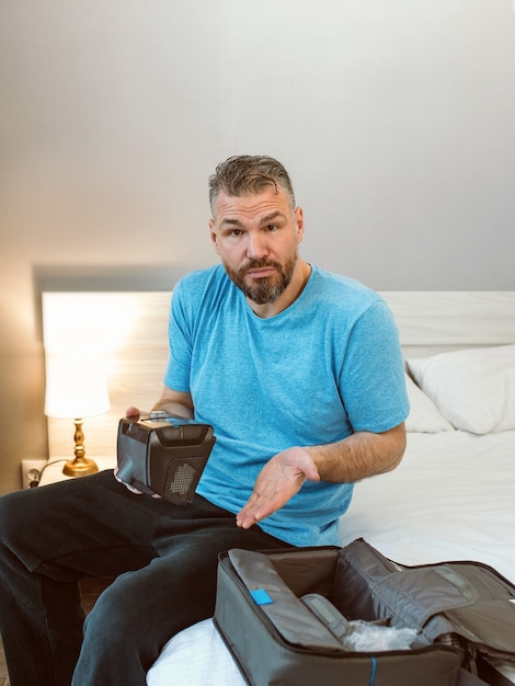 infelice uomo scioccato con problemi respiratori cronici sorpreso dall'uso della macchina cpap seduto sul letto