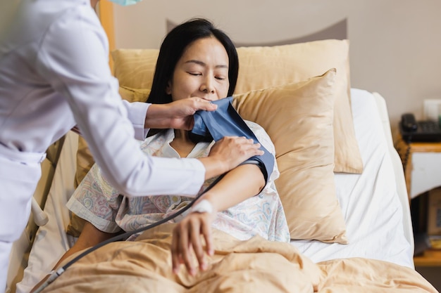 Infermiera che prende la pressione sanguigna del paziente femminile maturo nel letto d'ospedale