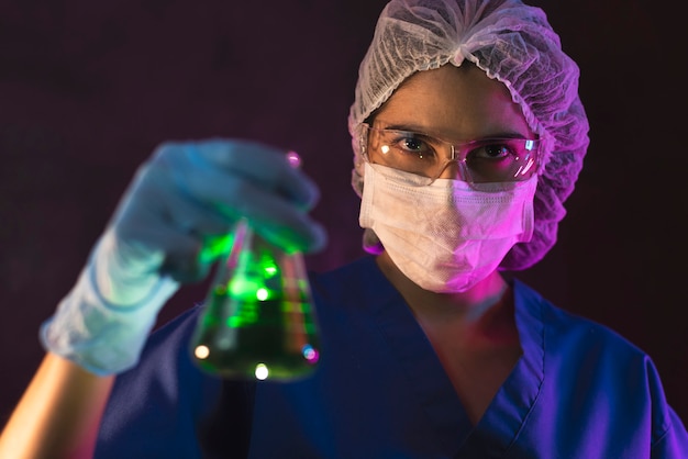 Infermiera con maschera antivirale all'interno di una stanza buia del laboratorio