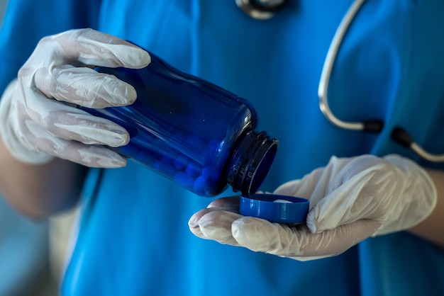 Infermiera in bottiglia uniforme blu della tenuta con le pillole bianche. concetto medico