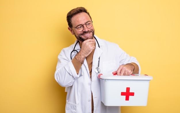 Infermiera o medico sorridente con un'espressione felice e sicura con la mano sul mento concetto di kit di pronto soccorso per affari e telefono