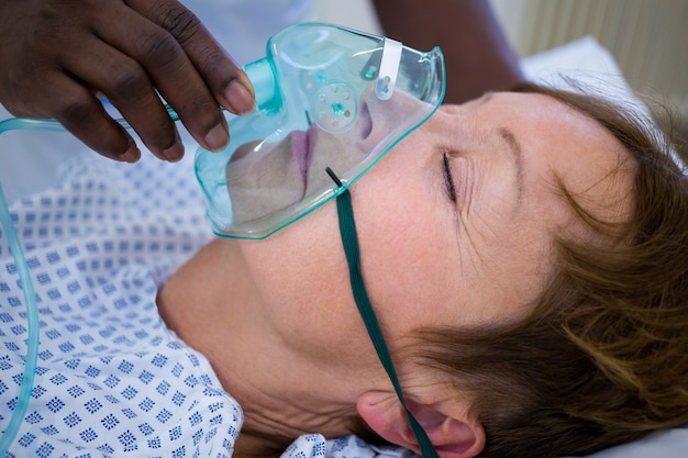 Infermiera posizionando una maschera di ossigeno sul viso di un paziente