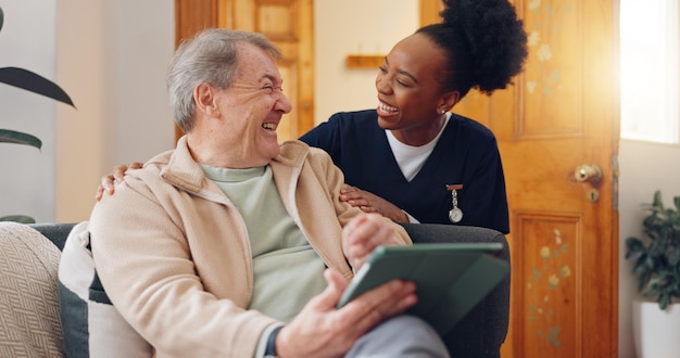 Infermiera su tablet e uomo anziano sul divano che navigano su Internet per ricerche di consultazione medica Bonding healthcare e caregiver donna nera che parlano con pazienti anziani networking sulla tecnologia a casa