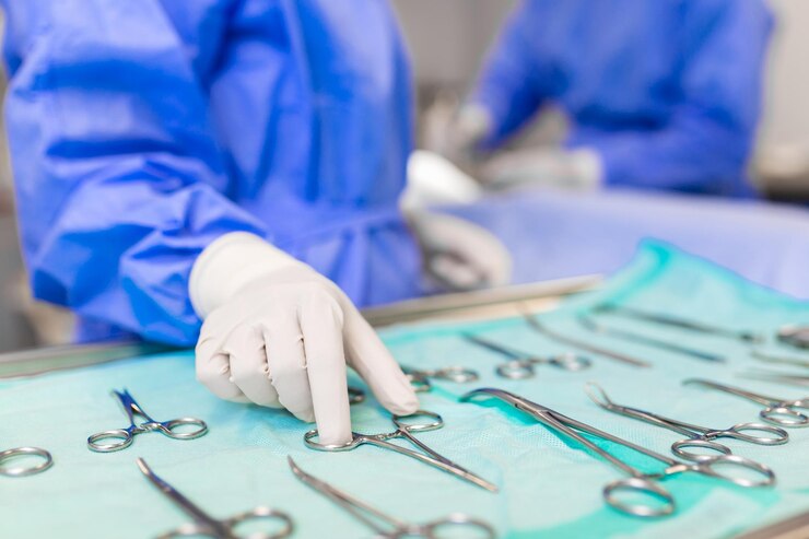 Infermiere che prende a mano uno strumento chirurgico per un gruppo di chirurghi in background che opera il paziente in sala operatoria Strumenti medici in acciaio pronti per essere utilizzati Chirurgia e concetto di emergenza
