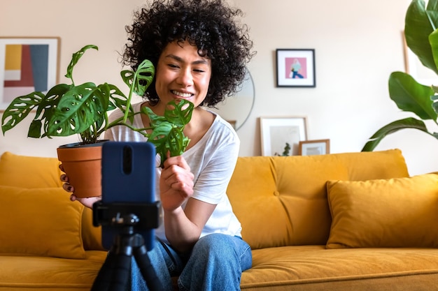 Influencer afroamericano che registra vlog a casa La donna ispanica live streaming mostra ai seguaci una pianta Spazio di copia Concetto di tecnologia