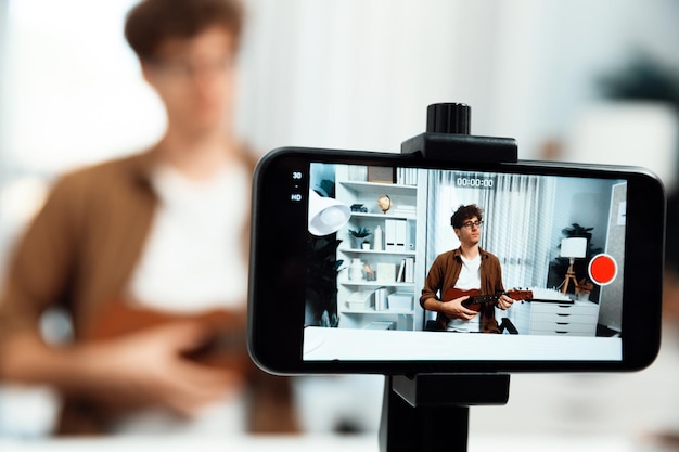 Influencer che canta, che suona la chitarra, che si concentra sul telefono, che vede lo sfondo sfocato, che scorre.