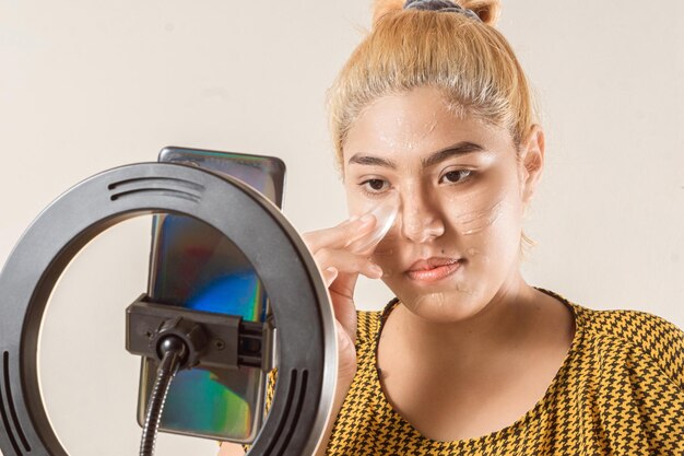 Influencer femminile che fa un video dal vivo con un telefono che si trucca