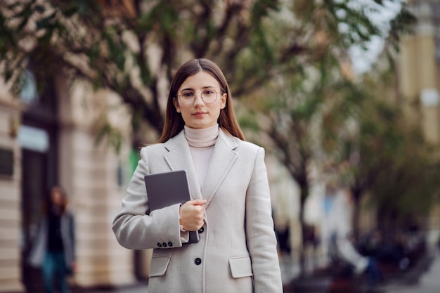 Influencer femminile in piedi sulla strada e tenendo il tablet nelle mani. Millennials e la loro vita sociale.