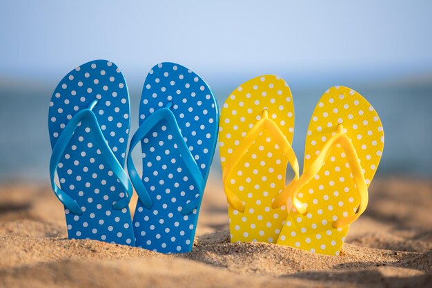 Infradito da spiaggia sulla sabbia contro lo sfondo del mare e del cielo Concetto di vacanza estiva