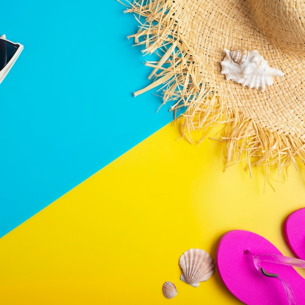 Infradito e conchiglie con cappello di paglia su sfondo giallo e blu mockup di pianificazione del viaggio per le vacanze