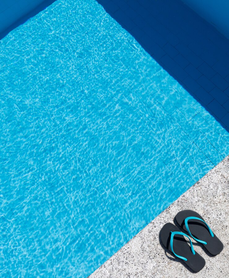 Infradito sul bordo di una piscina. Copia spazio. Vista dall'alto.